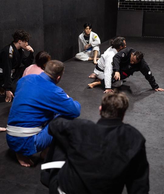 Group of martial arts students practicing under instructor supervision.